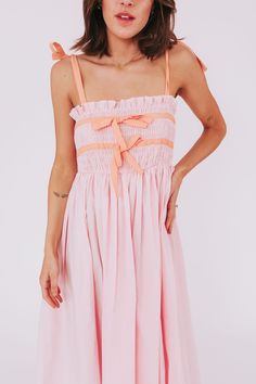 Get ready for a stylish and fun summer with our Sweet Simplicity Dress! This dress features tie straps and ribbons around the bodice for a unique look. The smocked top adds a touch of comfort and versatility. Perfect for any occasion, this dress is the epitome of sweet simplicity. Details Tie straps Ribbons around bodice Smocked top Baby pink with orange detailing Midi length Sizing Approximate measurements: SIZE LENGTH BUST Small 48" 26" Medium 51" 30" Large 53" 32" Fabric has in-bodice stretch Sleeveless Sundress With Bow Straps For Vacation, Spring Vacation Sundress With Bow Straps, Vacation Sundress With Knotted Ruffled Straps, Cute Dresses With Tie Straps For Vacation, Cute Vacation Dress With Tie Straps, Cute Vacation Dresses With Tie Straps, Beach Dresses With Knotted And Ruffled Straps, Cute Spring Sundress With Tie Straps, Spring Beach Sundress With Bow Straps