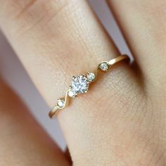 a woman's hand with a diamond ring on top of her finger and two diamonds in the middle