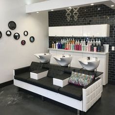 a salon with black and white furniture and lots of bottles on the wall