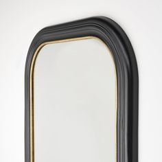 a black and gold framed mirror against a white wall