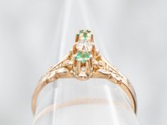 The warm glow of this antique gold is a lovely compliment to the brilliant green emeralds set on each side of the beautiful old mine-cut diamond! The details of the tiny prongs that surround each of these stones bring beauty and intricacy to this antique ring. Metal: 14K Antique Rose GoldGem: Old Mine Cut Diamond .11 CaratsGem Measurements: 2.4 mm, Round Accents: 2 Emeralds Ring Size: 5.50 Green Emerald Ring With Rose Cut Diamonds For Anniversary, Anniversary Green Emerald Ring With Rose Cut Diamonds, Art Deco Green Emerald Ring With Rose Cut Diamonds, Art Deco Emerald Ring With Rose Cut Diamonds, Green Emerald Cluster Ring With Rose Cut Diamonds, Green Cluster Ring With Rose Cut Diamonds, Green Emerald Cut Diamond Ring With Rose Cut Diamonds, Antique Green Emerald Cut Emerald Ring, Antique Emerald Cut Green Emerald Ring