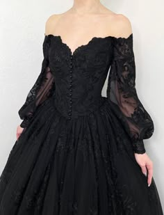 a woman is wearing a black dress with sheer sleeves and an off the shoulder neckline