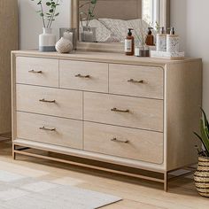 a bedroom with a dresser, mirror and potted plant