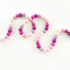 two bracelets made out of felt beads on a white surface with the word love spelled in pink and purple