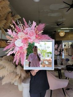 a woman holding up a photo frame with flowers on it in front of her face