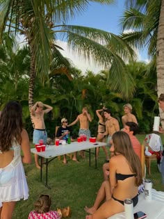 a group of people standing around a table with cups on it and one person in the foreground