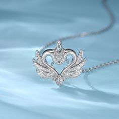 The pendant features two swans nestling tenderly together, creating an intimate scene. Their wings are decorated with sparkling gems, adding a touch of divine light between them. The swans' foreheads touch to form a heart shape, which reflects the close union of hearts. Give this symbol of devotion and let the embrace of the swan be an eternity in your journey together. Embrace the magic of love with this mesmerizing piece and witness the everlasting beautiful connection between you.Carat Weight Elegant Wing-shaped White Gold Necklace, Elegant White Gold Wing-shaped Necklace, Two Swans, Swan Jewelry, Swan Pendant, Swan Necklace, Silver Swan, Divine Light, The Embrace