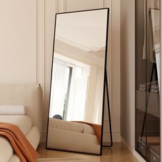 a large mirror sitting on top of a wooden floor next to a bed in a room