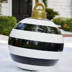 a black and white striped ball ornament on snow covered ground in front of a house