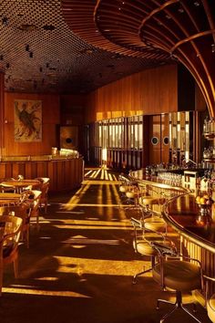 a dimly lit bar with wooden walls and tables in the foreground, along with stools on either side