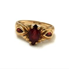 a gold ring with a red stone in it