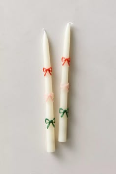 two candles with bows on them sitting next to each other