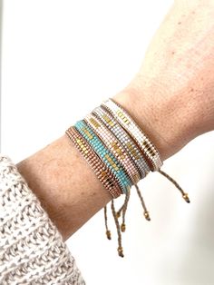 a woman's arm with several bracelets on it and one is wearing a white sweater