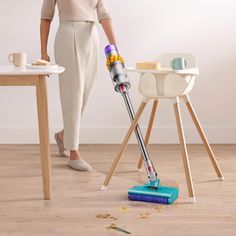 a woman is using a vacuum cleaner on the floor next to a table and chair