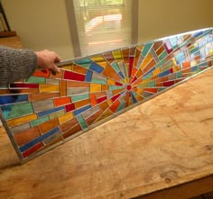 a person is holding up a stained glass piece that looks like a sunburst