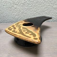 a small black and gold vase sitting on top of a wooden table