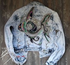 a jean jacket with an image of a fish on the back and some beads in it