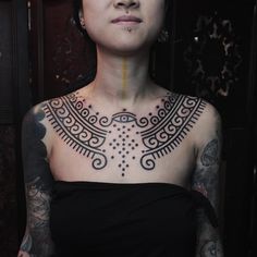 a woman with tattoos on her chest posing for the camera