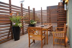 a wooden table and chairs sitting on top of a wooden deck next to a planter