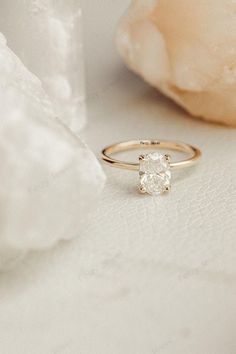 a close up view of a diamond ring on a white surface next to a flower