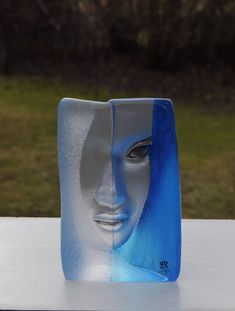 a blue and white vase sitting on top of a table next to a green field