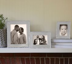 three frames are sitting on a mantle next to a potted plant