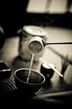 a spoon pouring water into a bowl on top of a table