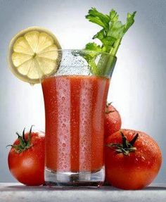 tomato juice with lime and mint in a tall glass surrounded by tomatoes on the table