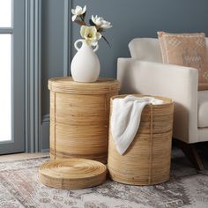 a white vase sitting on top of a wooden table next to two wicker baskets