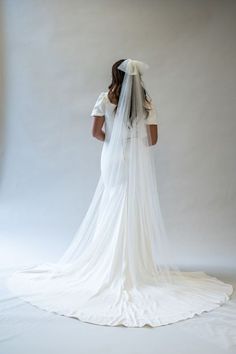 the back of a woman's wedding dress, with veil draped over her head