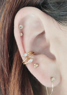 a woman wearing three different types of ear piercings