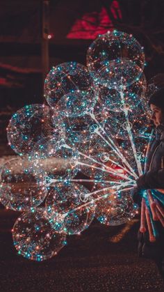 a man standing next to a bunch of bubbles that look like fireworks and stars in the sky