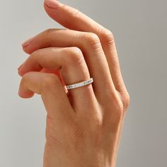 a woman's hand with a wedding band on her finger and the ring is in white gold