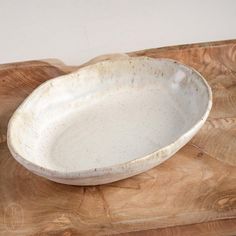 a white bowl sitting on top of a wooden cutting board