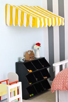 a child's room with striped walls and yellow and white awning over the bed