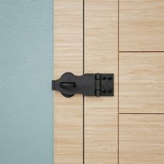 a close up of a door handle on a wooden door with blue walls in the background