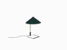 a green umbrella lamp sitting on top of a white table next to a black cord