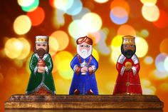 three figurines sitting on top of a wooden box with lights in the background