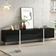 a modern black and white sideboard in a living room with a plant on top