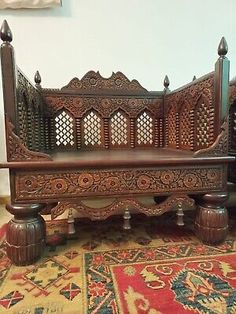 an ornate wooden bed frame sitting on top of a rug