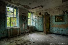 an old run down room with two windows and a ladder leaning against the wall in front of it