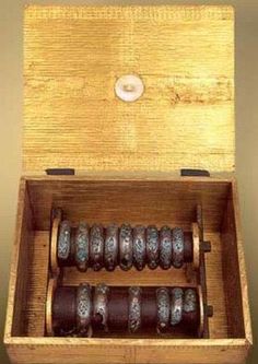 an open wooden box with several metal objects inside