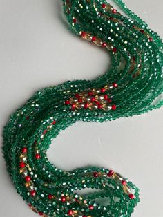 Elastic waist beads, made by skilled artisans in the Ivory Coast. This striking piece features deep green crystal glass seed beads complemented by vibrant red crystal glass seed bead accents, blending nature's tranquility with bold energy. Cultural Significance: In the Ivory Coast, waist beads hold deep cultural meaning as symbols of femininity, sensuality, and personal growth. Traditionally worn to celebrate significant life events, these beads connect wearers to their heritage and empower their personal journeys. Design and Craftsmanship: Materials: High-quality crystal glass seed beads Colors: Deep Green: Represents growth, harmony, and renewal Red Accents: Symbolizes passion, vitality, and strength Fit: Elastic band ensures a comfortable and flexible fit for all body types Wear with Pu Gemstone Waist Beads As Gift, Gift Gemstone Waist Beads, Green Multi-strand Beads For Gifts, Traditional Green Beaded Bracelets With Spacer Beads, Bohemian Green Waist Beads With Colorful Beads, Green Tiny Round Beads Waist Beads, Festive Green Beaded Bracelets With Colorful Beads, Festive Green Beaded Bracelets, Green Gemstone Party Beads