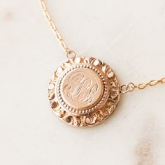 This one-of-a-kind necklace is composed of: Victorian medallion from the late 1800s with the initials "GLB" hand-engraved in the center. This necklace measures a standard 18” on a modern 14k gold filled chain, with the pendant measuring 0.875" in height. Etched 14k Rose Gold Jewelry, Elegant Engraved Initial Pendant Medallion Necklace, Rose Gold Medallion Necklace For Wedding, Etched Round Rose Gold Jewelry, Victorian Style Medallion Coin Pendant Jewelry, Personalized Brass Medallion Necklaces, Engraved Rose Gold Pendant Locket Necklace, Rose Gold Medallion Necklace For Anniversary, Engraved 14k Rose Gold Locket Necklace