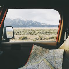 a map is sitting in the back seat of a car with mountains in the background