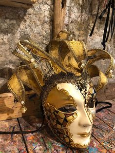 Original hand-painted Venetian mask embellished with gold leaf, stucco decoration, acrylic colors and precious fabrics. -Material/Resin Made in Italy hypoallergenic and anatoxic -Size/50x40Unisex -History of the mask/the Jester or joker is a mask that appears in Venice in 1970, the year in which the Venetian Carnival returns to its former glory after being interrupted during the Napoleonic (1700') and Austro-Hungarian (1800') dominations. Formerly a symbol of transgression and pleasure-loving li Traditional Masks And Prosthetics For Mardi Gras Carnival, Traditional Masks For Mardi Gras Carnival, Gold Fantasy Festival Masks And Prosthetics, Gold Masks And Prosthetics For Carnival Festival, Venetian Masks For Mardi Gras Carnival, Gold Masquerade Mask For Mardi Gras Festival, Traditional Masks And Prosthetics For Carnival, Artistic Masquerade Mask For Carnival Festivals, Multicolor Masquerade Mask For Carnival Festivals