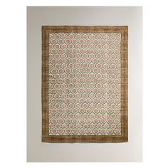 an old rug hanging on the wall with a brown border and tan trim around it