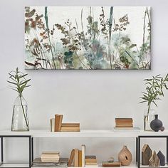 a white shelf with books and vases on top of it next to a painting