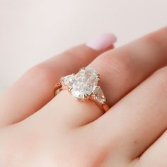 a woman's hand holding an engagement ring with two pear shaped diamonds on it