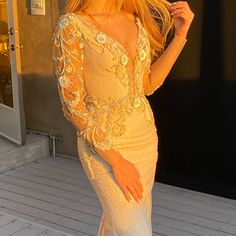 a woman in a white dress standing on a deck with her hand on her hip